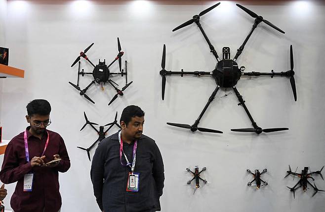 인도 뉴델리에서 열린 '국제 경찰·드론 엑스포 2026(International Police and Drone Expo 2026)'에서 전시업체 관계자들이 전시된 드론 옆에 서 있다. /AFP