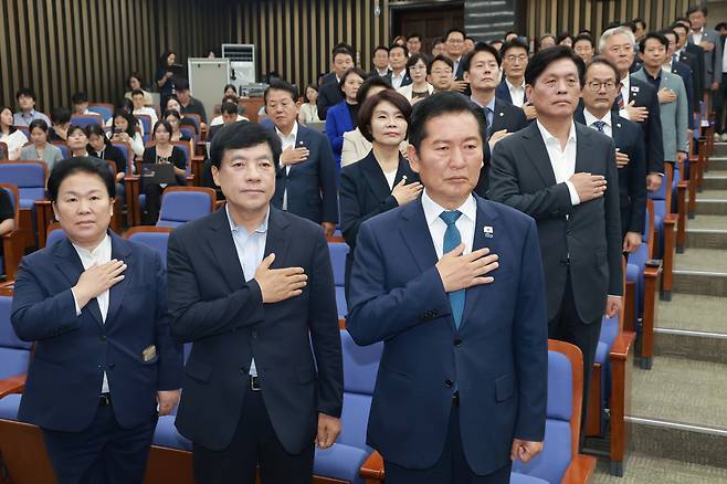 정청래 전 더불어민주당 대표(맨앞 줄 오른쪽)와 민주당 의원들이 지난 18일 국회에서 본회의를 앞두고 열린 의원총회에 참석해 국기에 경례하고 있다. 연합뉴스