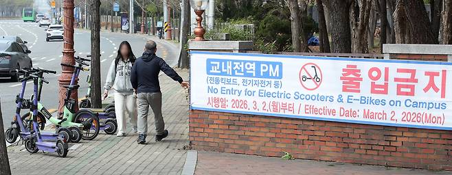 대구 달서구의 한 대학교 울타리 주변에 세워진 전동킥보드 등 개인형 이동장치(PM). 캠퍼스 내 전동킥보드 출입을 금지하는 경고문이 보인다. /뉴스1