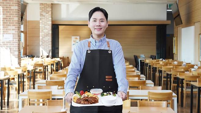 최영훈 동원홈푸드 대리가 영양사로 근무했던 시절을 추억하며 급식판을 들고 있다. 그는 "군에서는 취사병으로서 직접 음식을 만드는 경험을 했다면 입사 후에는 영양사로서 식단 기획, 위생 관리, 원가 관리 등 운영 전반을 책임졌다"며 "현장에서 직접 조리를 해본 경험이 영양사 일을 하는 데도 중요한 밑거름이 됐다"고 말했다. 동원그룹 제공