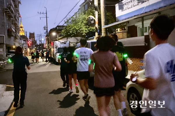 지난 25일 저녁 수원시 팔달구 골목 일대에서 ‘팔달 나이트런’ 참가자들이 팔에 야광 표식을 달고 경찰관과 나란히 달리고 있다. 주민 불편을 최소화하기 위해 조용히 달리다 위험 지점이 나오면 멈춰 서서 살폈다. 2026.6.25 /유혜연기자 pi@kyeongin.com