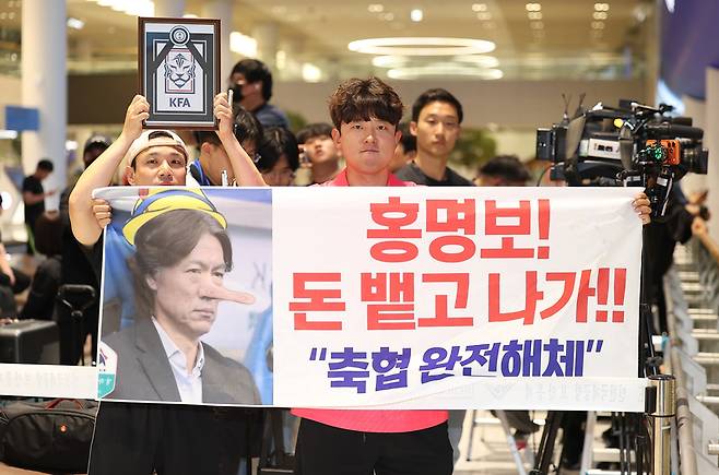▲ 2026 북중미 월드컵 32강 진출에 실패해 한국 축구 국가대표팀에서 사퇴한 홍명보 전 감독이 입국하는 30일 인천국제공항 제2여객터미널을 찾은 팬들이 항의 현수막을 들어올리고 있다. 연합뉴스
