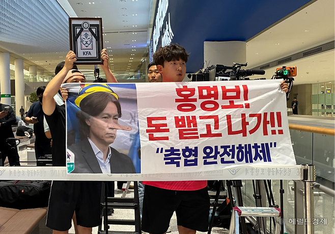 30일 오전 3시께 인천국제공항에서 조성근(38)씨가 항의 문구를 새긴 플래카드를 들고 홍명보 축구대표팀 감독을 기다리고 있다. 김서현 수습기자