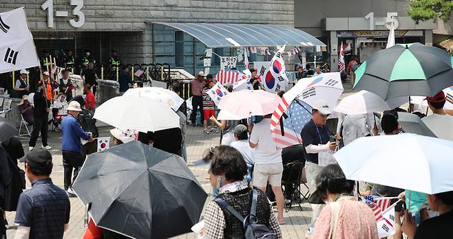 6·3 지방선거 당시 잠실 개표소로 사용된 서울 송파구 올림픽공원 핸드볼경기장 앞에서 지난달 28일 투표용지 부족 사태 규탄 봉쇄 시위 참가자들이 우산을 쓰고 구호를 외치고 있다. [연합뉴스]
