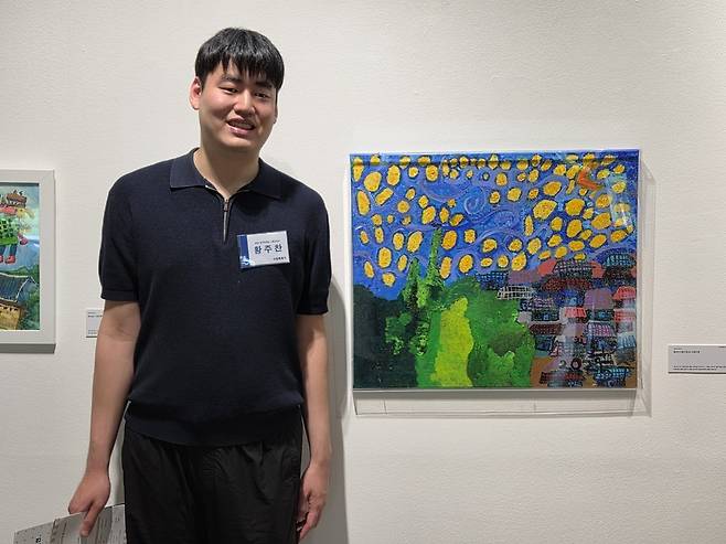 ▲ '처음이기에 더욱 특별한 이야기: 2026 발달장애인 그림 공모전'에서 성인부 최우수상을 수상한 황주찬 작가가 수상작 앞에서 포즈를 취하고 있는 모습. /박지혜 기자 pjh@incheonilbo.com