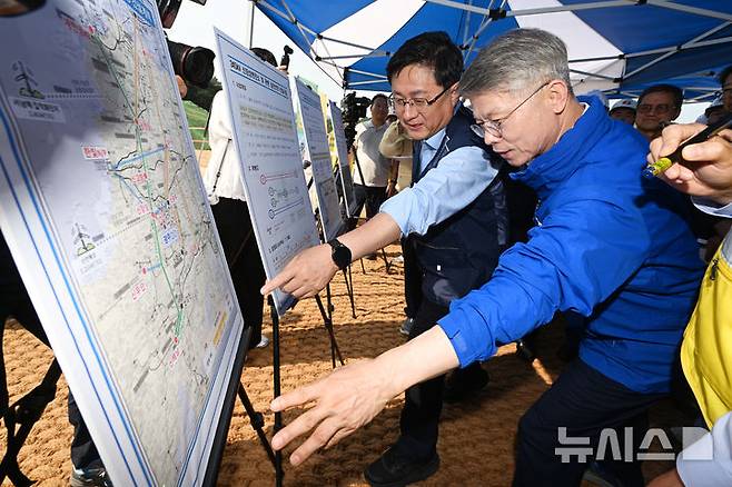 [장성=뉴시스] 이영주 기자 = 김성환(가운데) 기후부장관과 민형배 전남광주통합특별시장 당선인이 30일 오전 전남 장성군 동화면 신장성변전소 공사 현장에서 한국전력의 서남권 반도체 산단 조성 관련 전력망 건설 계획도를 보고 있다. 2026.06.30. leeyj2578@newsis.com