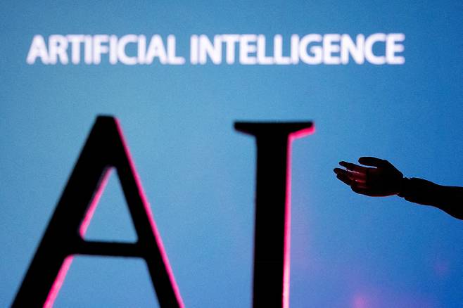 The letters AI and a robot hand miniature are seen in this illustration taken on June 23, 2023. REUTERS/YONHAP