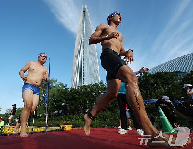 12일 오전 서울 송파구 석촌호수와 롯데월드타워 일원에서 열린 '2026 롯데 아쿠아슬론'에서 수영을 마친 참가자들이 수직마라톤을 위해 롯데월드타워로 향해 달리고 있다. (공동취재) 2026.7.12 ⓒ 뉴스1 구윤성 기자