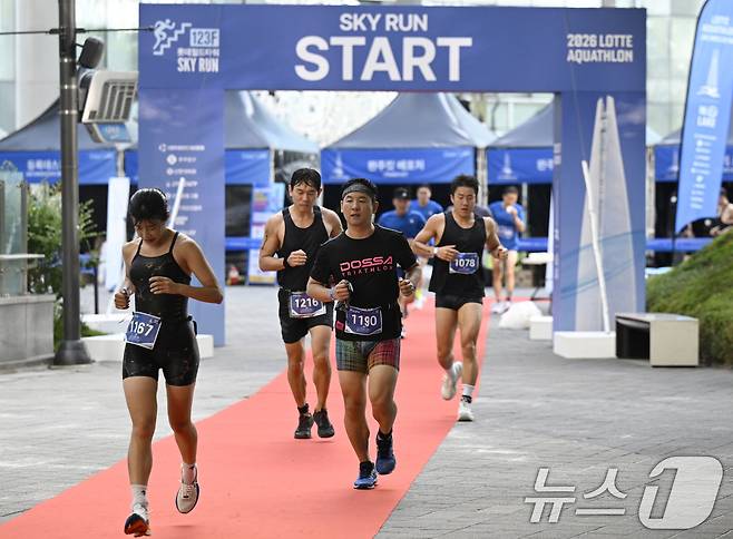 12일 오전 서울 송파구 석촌호수와 롯데월드타워 일원에서 열린 '2026 롯데 아쿠아슬론'에서 수영을 마친 참가자들이 수직마라톤을 위해 롯데월드타워로 향해 달리고 있다. (공동취재) 2026.7.12 ⓒ 뉴스1 구윤성 기자