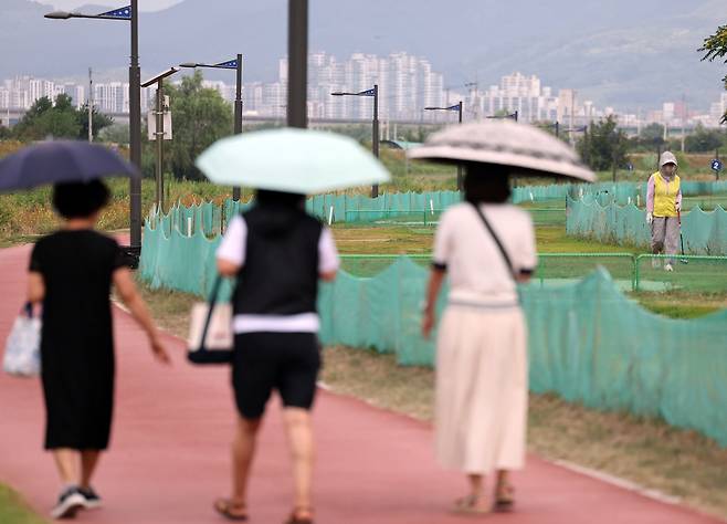 '양산은 필수'  (경산=연합뉴스) 김현태 기자 = 12일 경북 경산시 남천 둔치에서 시민들이 양산을 쓰고 산책하고 있다. 2026.7.12
 mtkht@yna.co.kr