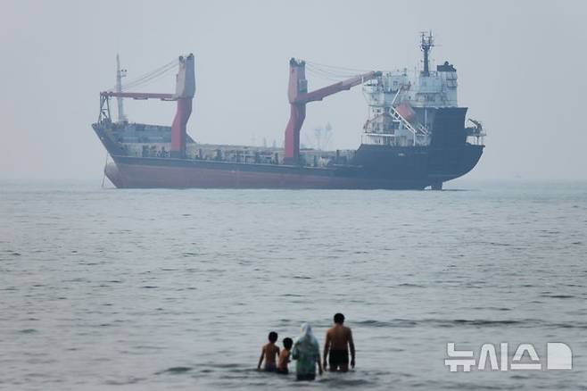 [반다르아바스=AP/뉴시스] 도널드 트럼프 미국 대통령이 예고한 대이란 해상봉쇄가 미 동부시간 14일 오후 4시(한국시간 15일 오전 5시)부터 시행된다. 미 중부사령부(CENTCOM)는 13일 엑스(X·옛 트위터)를 통해 도널드 트럼프 미국 대통령의 지시에 따라 이란 항구를 출입하는 해상 교통에 대한 봉쇄를 재개한다고 밝혔다. 사진은 지난 6월30일(현지시간) 이란 반다르아바스 앞 호르무즈 해협에서 화물선 한 척이 정박해 있는 가운데 사람들이 얕은 물에 서 있다. 2026.07.09.