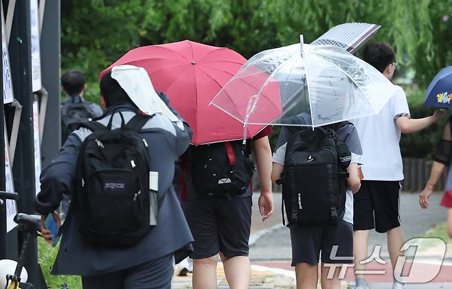 14일 경기 수원시의 한 도로에서 학생들이 우산을 쓰고 하교를 하고 있다. 2026.7.14 ⓒ 뉴스1 김영운 기자
