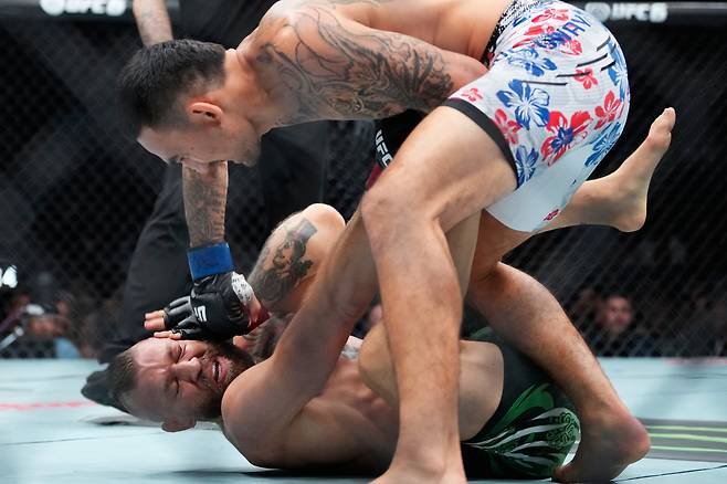 넘어진 코너 맥그리거(아래)에게 파운딩을 쏟아내는 맥스 할로웨이. 사진=AP 연합뉴스