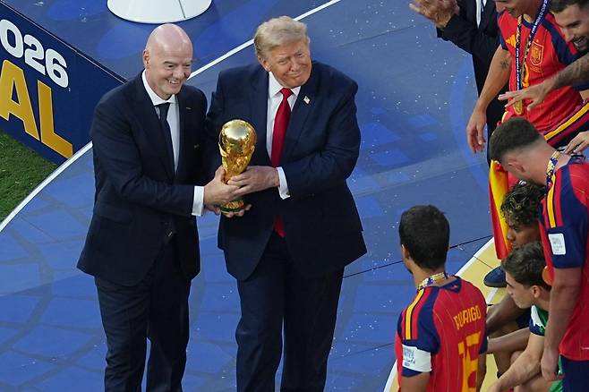잔니 인판티노 국제축구연맹(FIFA) 회장(왼쪽)과 도널드 트럼프 미국 대통령이 20일 열린 2026 북중미 월드컵 결승전이 끝난 뒤 스페인 축구 대표팀 주장 로드리에게 우승 트로피를 전달하고 있다. 이스트러더퍼드=AP 뉴시스