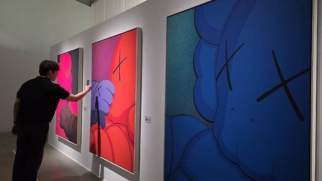 [사진=박현주 미술전문기자]관람객이 카우스(KAWS)의 회화를 휴대전화에 담고 있다. *재판매 및 DB 금지