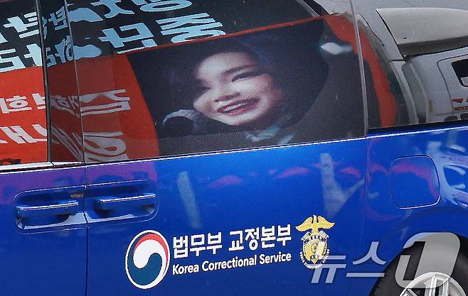 김건희 여사를 태운 호송차가 22일 경기 과천 2차 종합특검 사무실 지하주차장으로 들어서고 있다. 김여사가 탄 차량에 지지자들이 마련한 김 여사 사진이 비춰지고 있다. 2차 종합특검팀(특별검사 권창영)은 이날 윤석열 전 대통령 관저 이전과 관련 특정범죄가중처벌법상 알선수재와 직권남용 혐의로 김 여사를 피의자 신분으로 소환했다. 2026.7.22 ⓒ 뉴스1 이호윤 기자