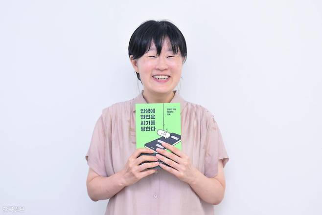 12일 서울 노원구 공유오피스에서 '인생에 한번은 사기를 당한다' 저자 김수량씨가 책을 들고 웃음 짓고 있다. 최주연 기자