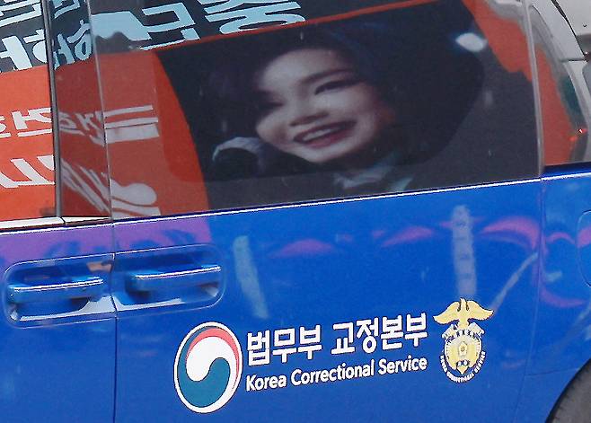 김건희 여사를 태운 호송차가 22일 경기 과천 2차 종합특검 사무실 지하주차장으로 들어서고 있다. 김여사가 탄 차량에 지지자들이 마련한 김 여사 사진이 비춰지고 있다. 2차 종합특검팀(특별검사 권창영)은 이날 윤석열 전 대통령 관저 이전과 관련 특정범죄가중처벌법상 알선수재와 직권남용 혐의로 김 여사를 피의자 신분으로 소환했다. 뉴스1