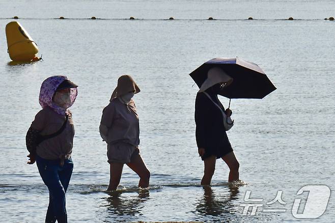 경북 포항지역에 폭염경보가 발령된 23일 오전 경북 포항시 북구 영일대해수욕장에서 우산을 든 시민이 바닷물에 발을 담그고 있다. 2026.7.23 ⓒ 뉴스1 최창호 기자