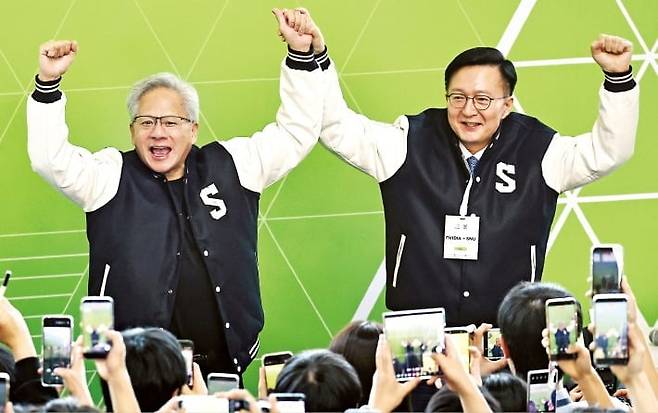 젠슨 황 엔비디아 최고경영자(CEO·왼쪽)가 지난달 8일 서울대 해동첨단공학관에서 열린 ‘빌드어클로’ 행사장에서 유홍림 서울대 총장에게 학교 점퍼를 선물 받은 뒤 함께 손을 흔들고 있다.  /연합뉴스