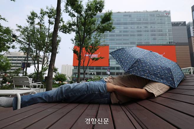 무더운 날씨가 이어진 지난 16일 서울 광화문광장에서 한 시민이 양산으로 햇볕을 가린 채 누워있다. 정효진 기자