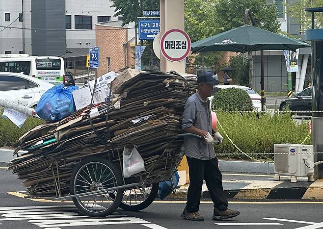 폭염경보가 발효된 27일 전남광주통합특별시 북구 용봉동에서 한 노인이 폐지를 가득 실은 리어카를 끌고 있다. 이날 최고기온은 34.7도, 체감온도는 35.3도까지 치솟은 가운데 생계를 위해 폐지를 모으는 노인들의 발걸음은 계속됐다./윤찬웅 기자