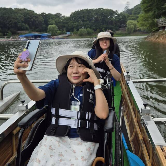 저신장 장애인 이유정(앞쪽)씨와 뇌병변 장애인 정은지씨가 23일 경기 파주시 마장호수에서 휠체어를 탄 채 이용 가능한 무장애 킹카누 체험을 하고 있다. 정인선 기자