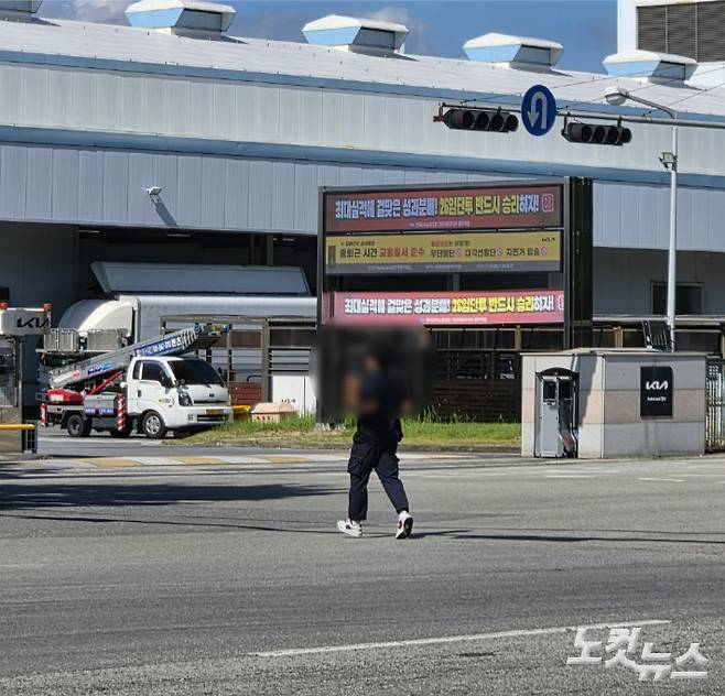 30일 오후 전남광주 서구 기아 광주1공장 남문 앞에서 한 직원이 횡단보도를 벗어나 도로를 가로질러 이동하고 있다. 공장 측이 남문 앞에 교통질서 준수를 당부하는 현수막을 설치했지만 무단횡단은 이어지고 있다. 정유철 기자
