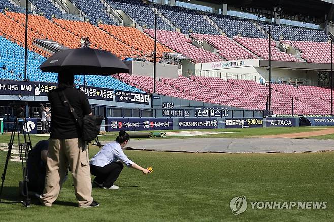 취재진만 남은 그라운드 (서울=연합뉴스) 서대연 기자 = 전국을 뒤덮은 폭염에 오늘과 내일 열릴 예정이었던 프로야구 1, 2군 경기가 모두 취소된 5일 서울 송파구 잠실야구장에서 취재진이 그라운드 온도를 재고있다.
한국야구위원회(KBO) 사무국은 프로 10개 구단 단장과 프로야구선수협회 관계자가 참석하는 폭염 긴급 대책 회의를 6일 열어 관중과 선수단의 안전을 최우선으로 삼은 리그 운영과 안전 대책을 원점에서 논의하겠다고 밝혔다. 장기 종합 대책이 수립되기 전까지 5∼6일 프로야구 1, 2군 전 경기를 열지 않기로 했다. 2026.8.5 dwise@yna.co.kr