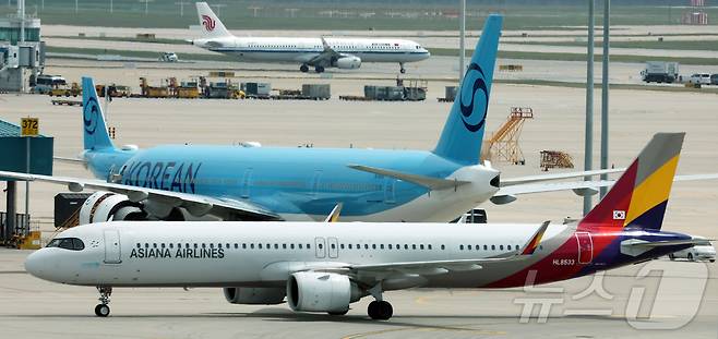 지난 5월 인천국제공항 제2터미널 계류장에서 아시아나항공 여객기(아래)와 대한항공 여객기(위)가 이동하는 모습. 2026.5.18 ⓒ 뉴스1 김진환 기자