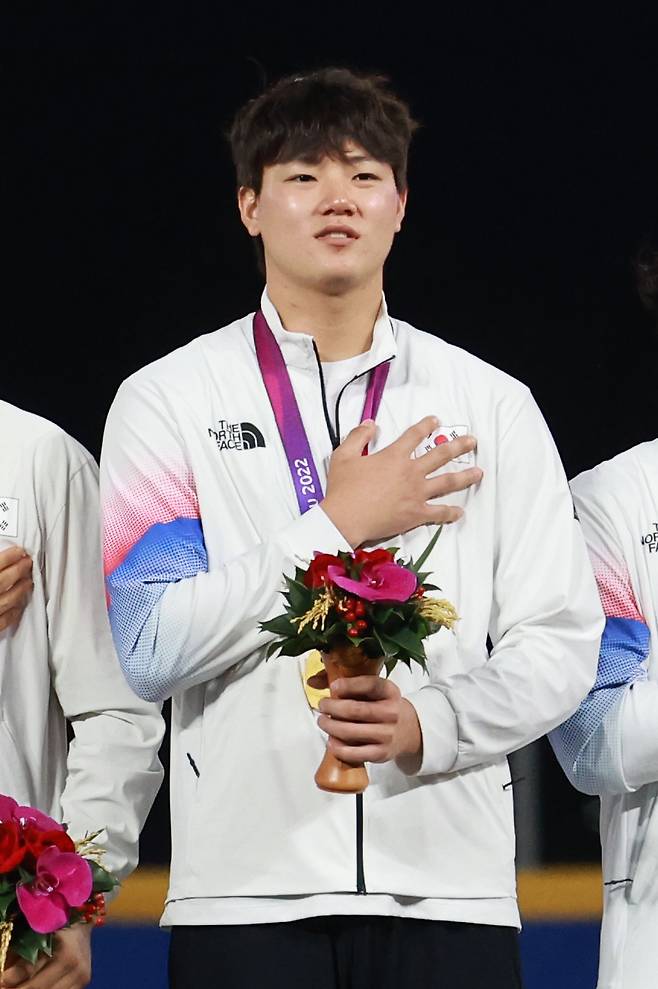 7일 중국 저장성 항저우 인근 사오싱 야구·소프트볼 스포츠센터 제1구장에서 열린 2022 항저우 아시안게임(AG) 결승, 대만과 대한민국의 경기에서 2-0으로 승리하며 금메달을 획득한 대한민국 투수 장현석이 시상식에서 메달을 목에 건 채 국기에 대한 경례를 하고 있다. 2023.10.8 [연합뉴스]