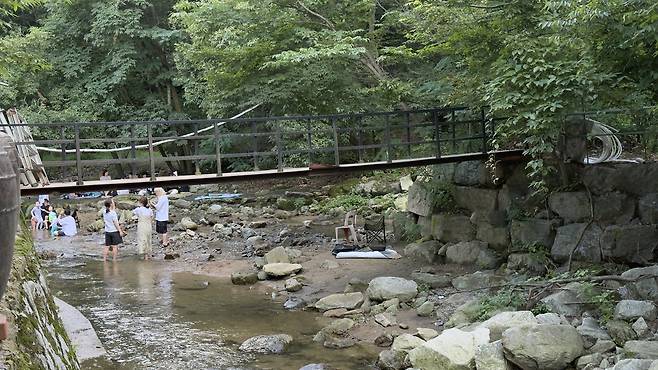 Diners from a samgyetang, or ginseng chicken soup, restaurant play in the stream directly in front of the restaurant. WOO JI-WON