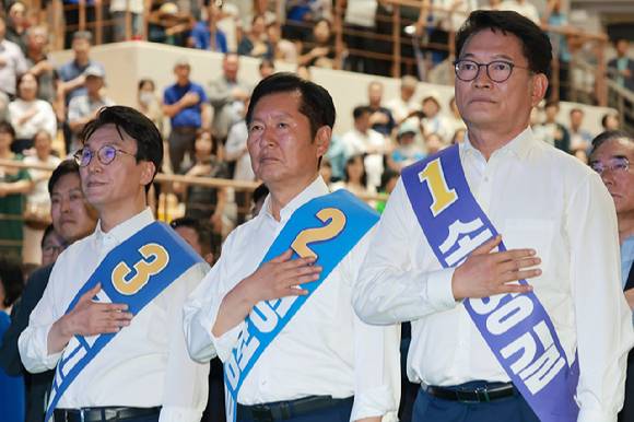 더불어민주당 김민석·정청래·송영길 당 대표 후보가 15일 전남광주 나주시 나주종합스포츠파크 다목적체육관에서 열린 민주당 대표·최고위원 전남광주 합동연설회에 참석해 국기에 경례하고 있다. 2026.8.15 [사진=연합뉴스]