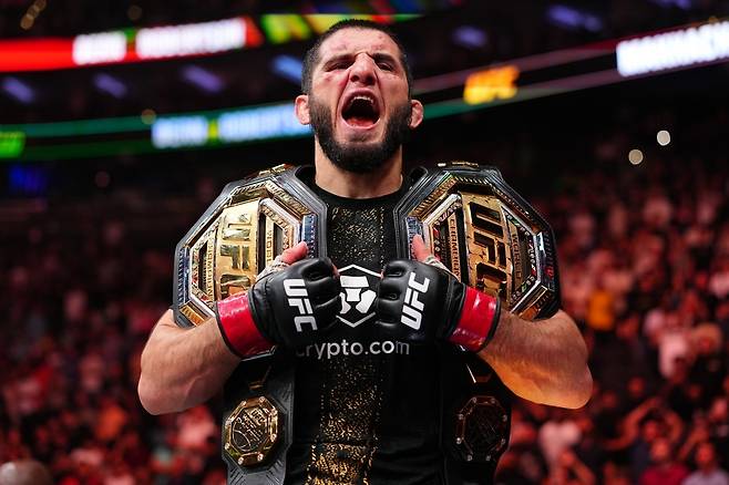 16일 UFC 330에서 이언 마샤두 개리에게 승리한 뒤 어깨에 라이트급, 웰터급 챔피언 벨트를 둘러메고 환호하는 이슬람 마카체프. 사실 라이트급 벨트는 웰터급 월장 전에 UFC에 의해 반납됐다. [UFC 제공]