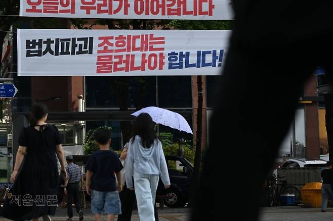 23일 서울 도심의 한 교차로 옆에 붙은 ‘법치파괴 조희대는 물러나야 합니다’는 글귀의 현수막 아래로 시민들이 지나가고 있다. 김민석 더불어민주당 대표는 지난 19일 이 같은 내용의 현수막을 전국에 걸라고 지시했다. 이지훈 기자