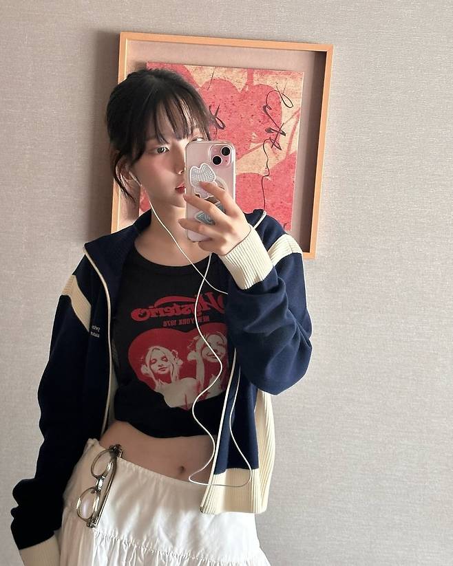 Karina, do Aespa, tira uma selfie no espelho com fones de ouvido com fio [Capturada do Instagram de Karina. Revenda e distribuição proibidas]