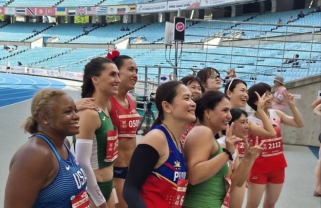 2026 대구세계마스터즈육상경기대회 100ｍ 종목에 출전한 강정연 선수가 경기 직후 세계 각국의 선수들과 함께 기념촬영을 하고 있다. 노진실 기자