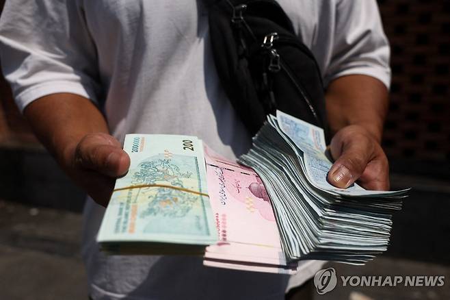 이란 수도 테헤란의 그랜드 바자르에서 리알화를 들고 있는 환전상 [로이터=연합뉴스 자료사진. 재판매 및 DB 금지]