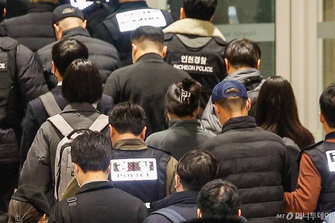 (인천공항=뉴스1) 안은나 기자 = 캄보디아를 거점으로 대규모 스캠(사기) 범죄 등을 저질른 한국 국적 피의자 73명이 강제 송환된 23일 오전 9시 36분 인천국제공항 2터미널에서 120억 원대 로맨스 스캠 범죄 총책 부부가 경찰에 붙잡혀 이송되고 있다. 2026.1.23/뉴스1  Copyright (C) 뉴스1. All rights reserved. 무단 전재 및 재배포,  AI학습 이용 금지.