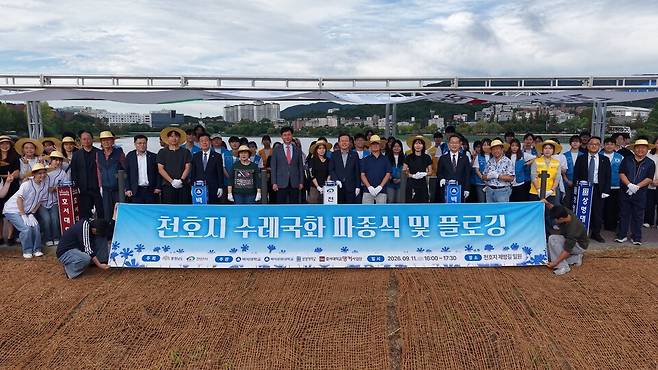 지난 11일 천안시 천호지 일원에서 열린 '천호지 수레국화 파종식 및 플로킹 행사'를 마치고 장기수 천안시장과, 대학생, 주민들이 기념촬영을 하고 있다. ⓒ천안시 제공