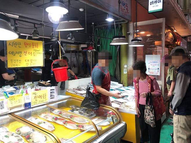 망원시장 생선가게에서 상인과 소비자가 흥정을 하고 있다. [사진=김유진 기자]