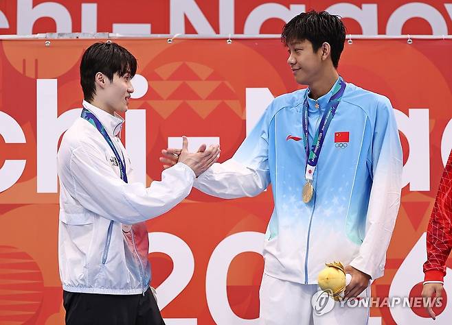 장잔숴와 악수하는 황선우 (도쿄=연합뉴스) 윤동진 기자 = 23일 도쿄 아쿠아틱스 센터에서 열린 2026 아이치·나고야 아시안게임 수영 남자 200m 개인 자유형 결승에서 은메달을 획득한 황선우(왼쪽)가 금메달을 획득한 중국의 장잔숴와 시상대에 올라 악수하고 있다. 2026.9.23 mon@yna.co.kr