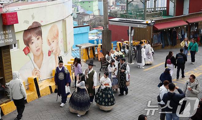 방탄소년단(BTS) 컴백 공연을 이틀 앞둔 19일 부산 서구 감천문화마을에서 외국인 관광객들이 부산이 고향인 BTS 멤버 정국·지민이 그려진 대형 벽화를 배경으로 기념촬영을 하고 있다. 2026.3.19 ⓒ 뉴스1 윤일지 기자