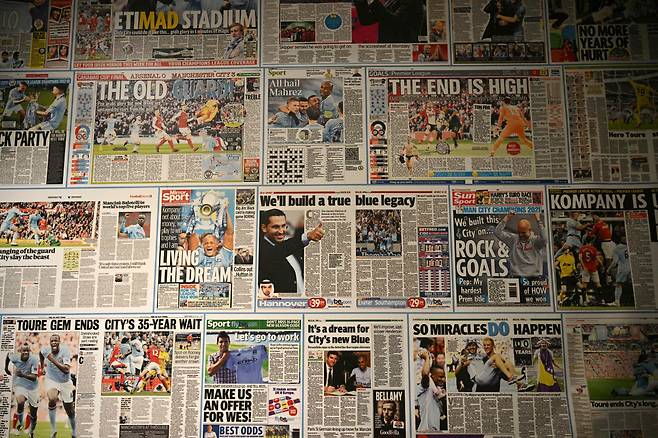 A wall covering featuring newspaper stories about Manchester City victories and trophy wins is pictured in the media area inside the Etihad Stadium, is pictured in Manchester, north-west England, on October 13, 2026. (Photo by Oli SCARFF / AFP)  <저작권자(c) 연합뉴스, 무단 전재-재배포, AI 학습 및 활용 금지>