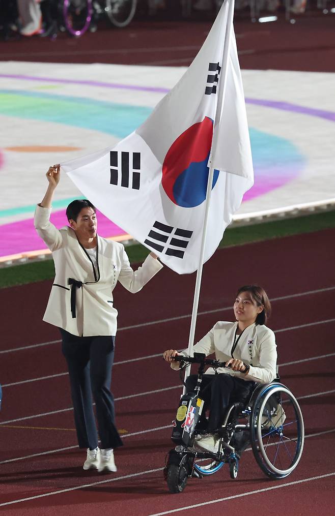 장민호(왼쪽)와 윤지유가 18일 일본 나고야 미즈호공원 육상경기장에서 열린 2026 아이치·나고야 아시안 패러게임 개회식에서 한국 선수단 기수로 입장하고 있다. /연합뉴스