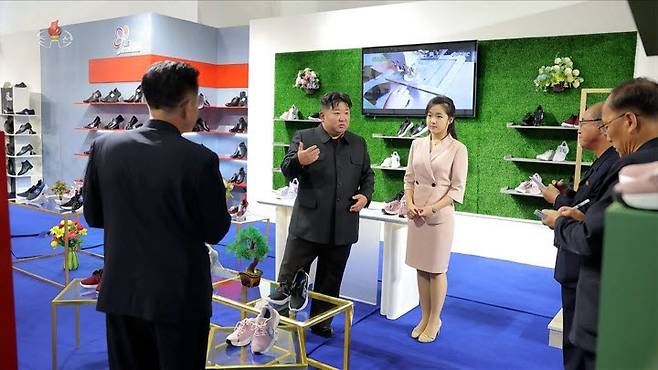 김정은 북한 국무위원장이 지난 19일 '전국피복, 신발전시회-2026'을 찾아 신발 전시대에서 딸 주애가 지켜보는 가운데 간부들과 이야기하고 있다 (사진=연합뉴스)