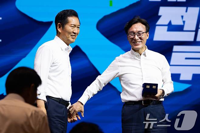 김민석 더불어민주당 대표가 27일 인천 영종구 인스파이어 엔터테인먼트 리조트에서 열린 2026년 정기국회 대비 국회의원 워크숍에서 정청래 전 대표에게 감사패 전달에 앞서 손을 잡고 있다. 2026.8.27 ⓒ 뉴스1 유승관 기자
