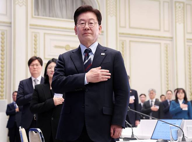 이재명 대통령이 지난 23일 청와대에서 열린 규제합리화위원회 2차 전체회의에서 국기에 경례하고 있다. 연합뉴스
