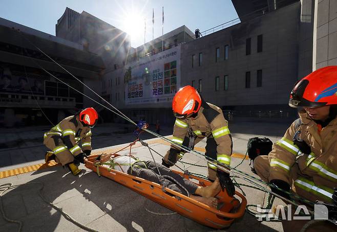 [서울=뉴시스] 홍효식 기자 = 26일 서울 종로구 세종문화회관 앞에서 종로구청과 종로소방서가 공동 주최·주관해 열린 2026 재난대비훈련에서 소방대원들이 환자를 구조하고 있다. 2026.10.26. yesphoto@newsis.com