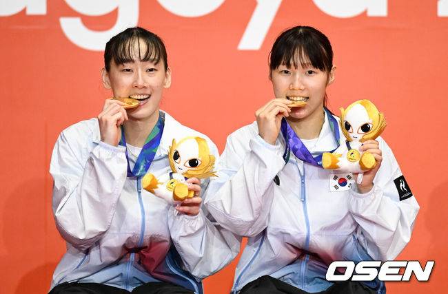 [OSEN=아이치현(일본), 박준형 기자] 마침내 한국 배드민턴의 2026&nbsp;아이치·나고야 아시안게임 첫 금메달이 탄생했다.&nbsp;이소희-백하나(이상 인천국제공항) 조가 명승부 끝에 만리장성을 넘고 여자복식 정상에 올랐다.&nbsp;배드민턴 여자 복식 세계 2위 이소희-백하나 조는 29일&nbsp;일본 이치노미야 시립 체육관에서 열린 대회 여자 복식 결승전에서&nbsp;중국의 류성수-탄닝 조(세계 1위)를 상대로 2-1(26-28 21-18 21-18)로 역전승을 거두며 우승했다.&nbsp;1게임 41분, 2게임 28분, 3게임 37분으로 총 106분이 걸린 혈투였다.이소희-백하나가 금메달을 물고 포즈를 취하고 있다.    2026.09.29 / soul1014@osen.co.kr